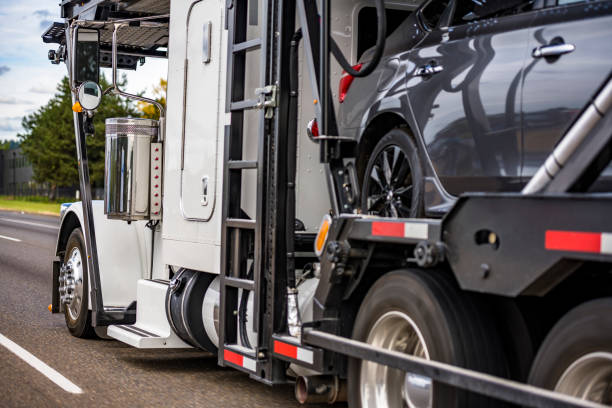 Industrial grade white big rig car hauler semi truck tractor with truck driver rest sleeping compartment transporting cars on the two level hydraulic semi trailer driving on the highway road